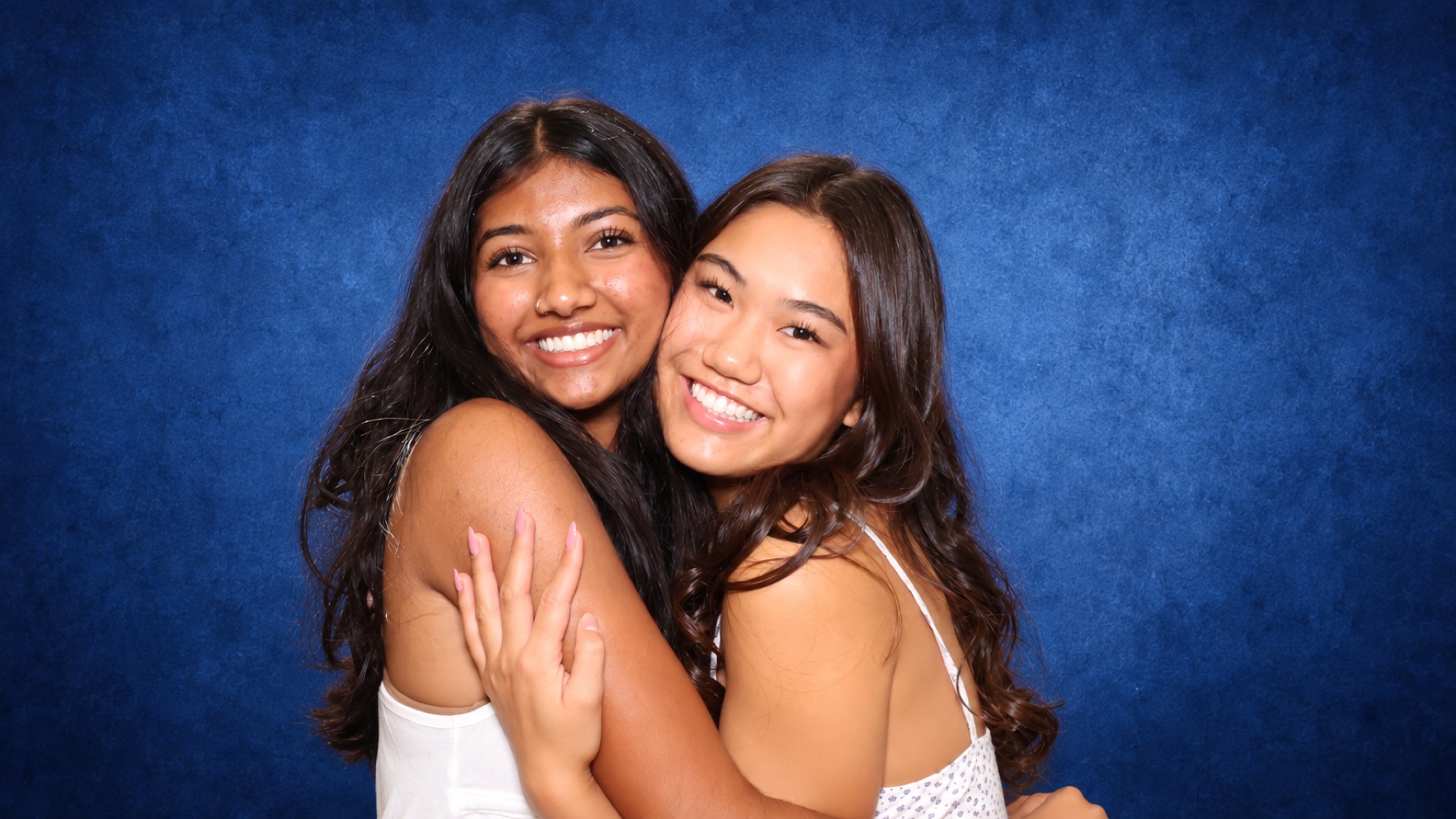 Two friends embracing in front of the midnight blue backdrop