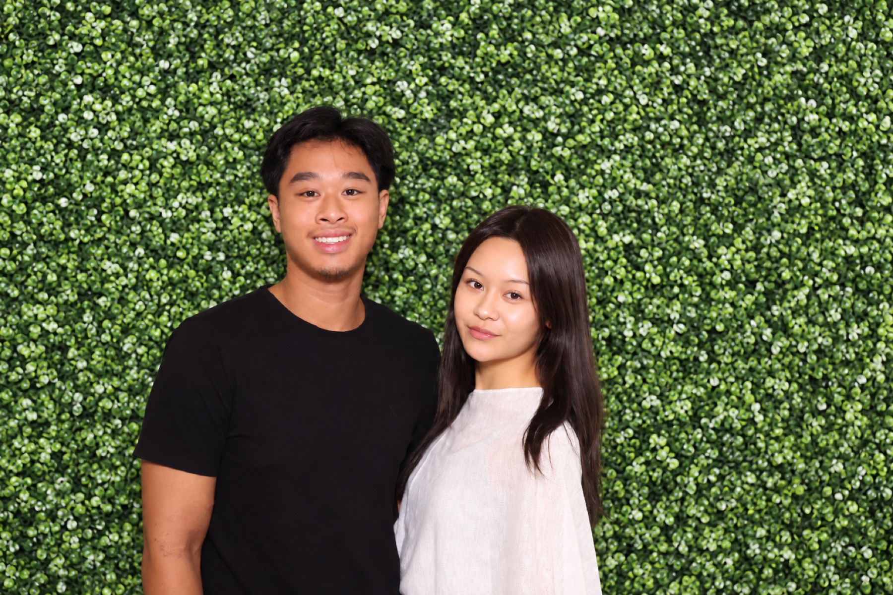 A couple posing together in front of the evergreen boxwood backdrop