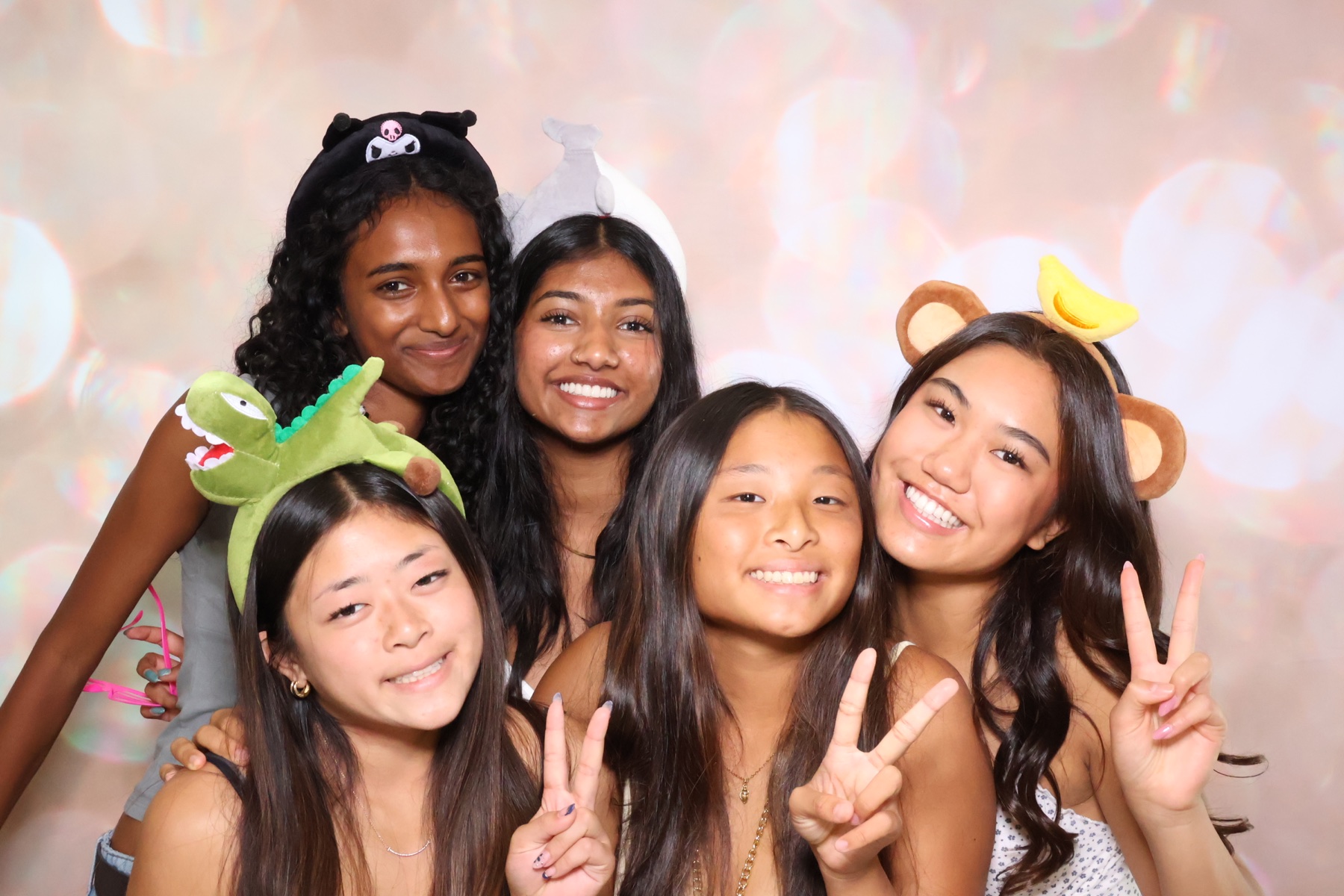 Friends posing with playful headband props at the photo booth